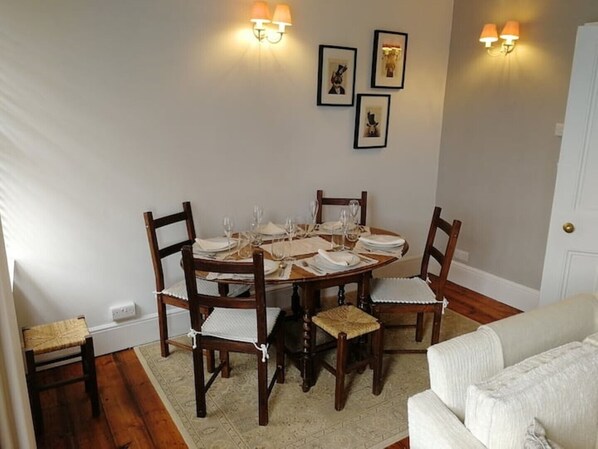 A dining area with a round table set for four, surrounded by wooden chairs with cushioned seats. - Gorgeous 3 bedroom home opposite beach. ! (Budleigh Salterton)