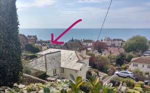 A residential area with a house featuring a sloped roof and a garden in the foreground. - Gorgeous 3 bedroom home opposite beach. ! (Budleigh Salterton)
