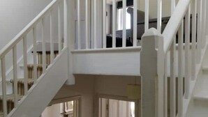 Un interior de varios niveles con barandillas blancas y una escalera.