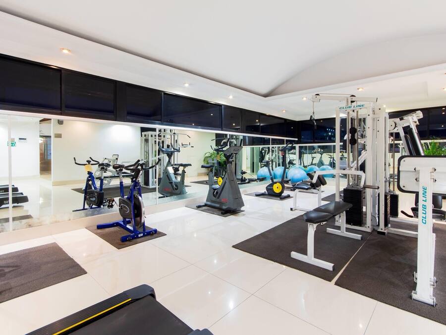 A modern gym with various exercise equipment, including treadmills, stationary bikes, and weight machines.