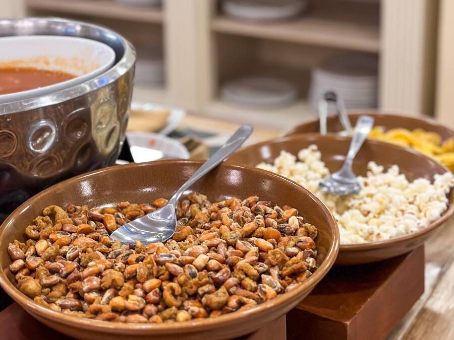 Una mesa de buffet con una variedad de platos, incluyendo un tazón grande de nueces mezcladas, un tazón de palomitas de maíz y un tazón de sopa.