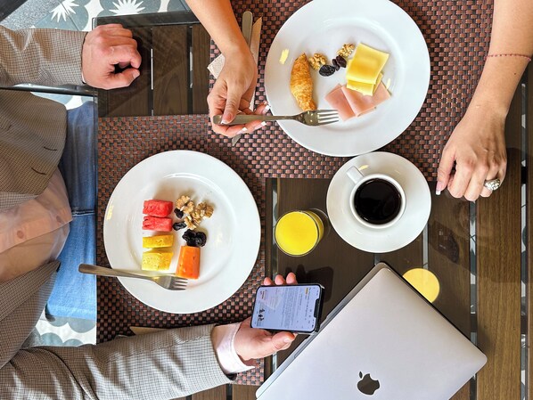 A table with breakfast items including croissants, fruits, and coffee.