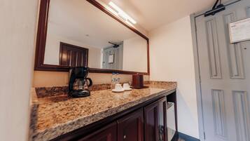 A kitchen with granite countertops, a coffee maker, and a mirror above the counter.