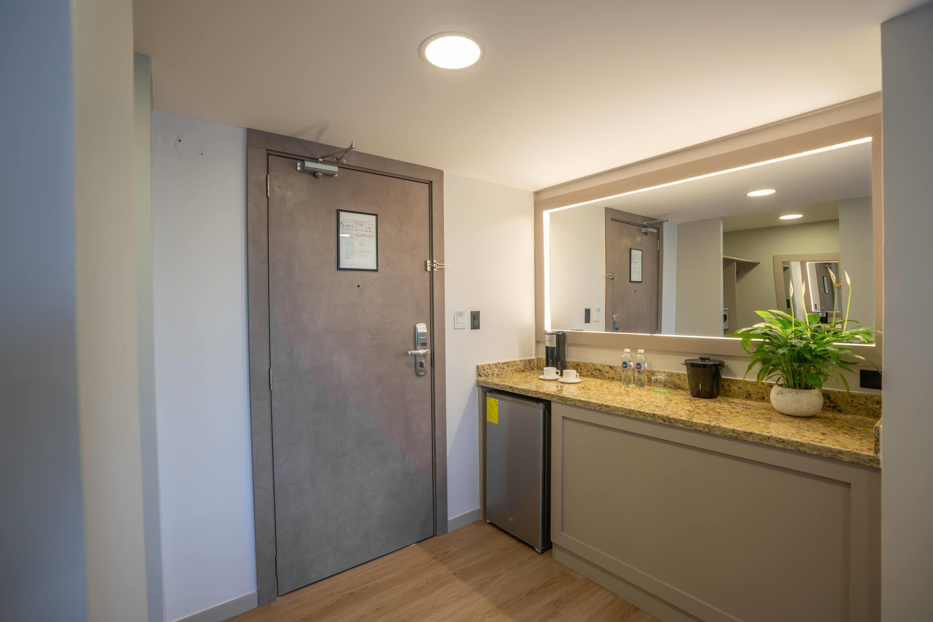 Un baño moderno con un espejo grande, un lavamanos y un mueble pequeño.