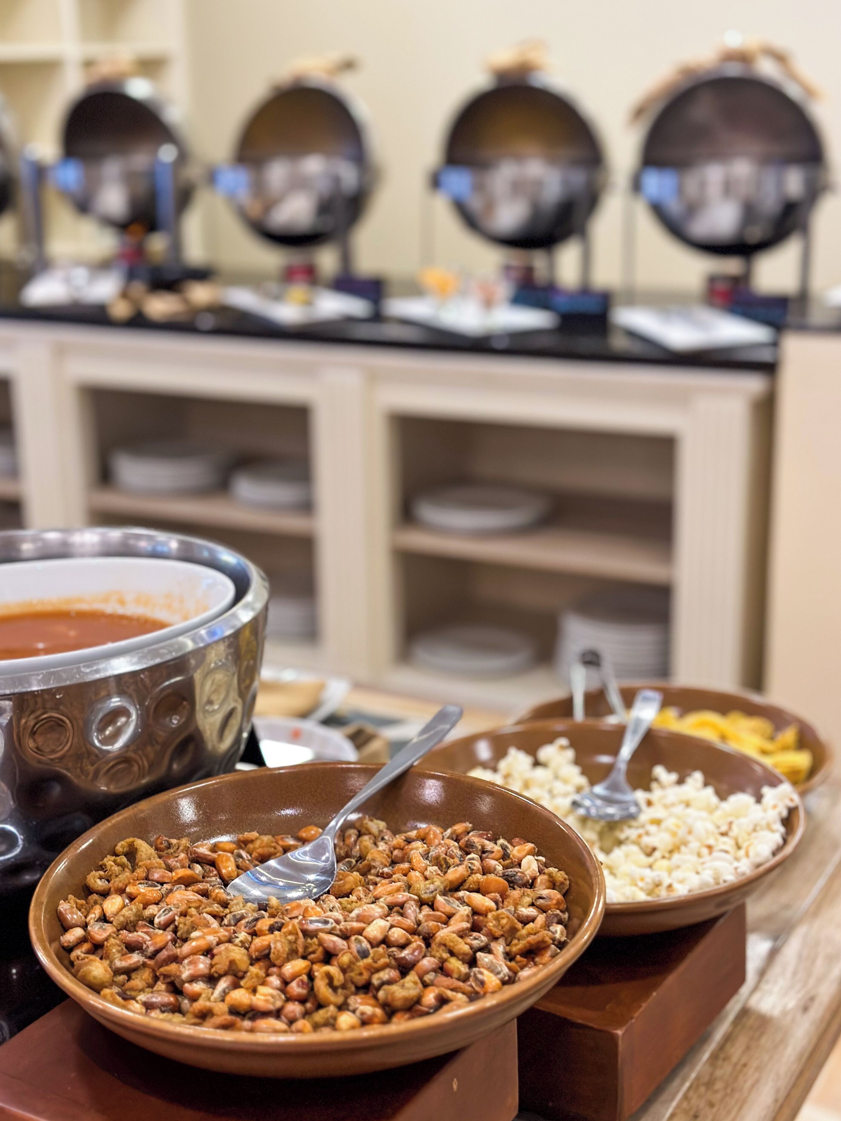 A buffet with various dishes including a large bowl of soup, bowls of mixed nuts, and bowls of rice.