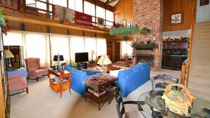 Ein geräumiges Wohnzimmer mit Kamin, blauen Sofas, einem Holztisch und einem Fernseher.