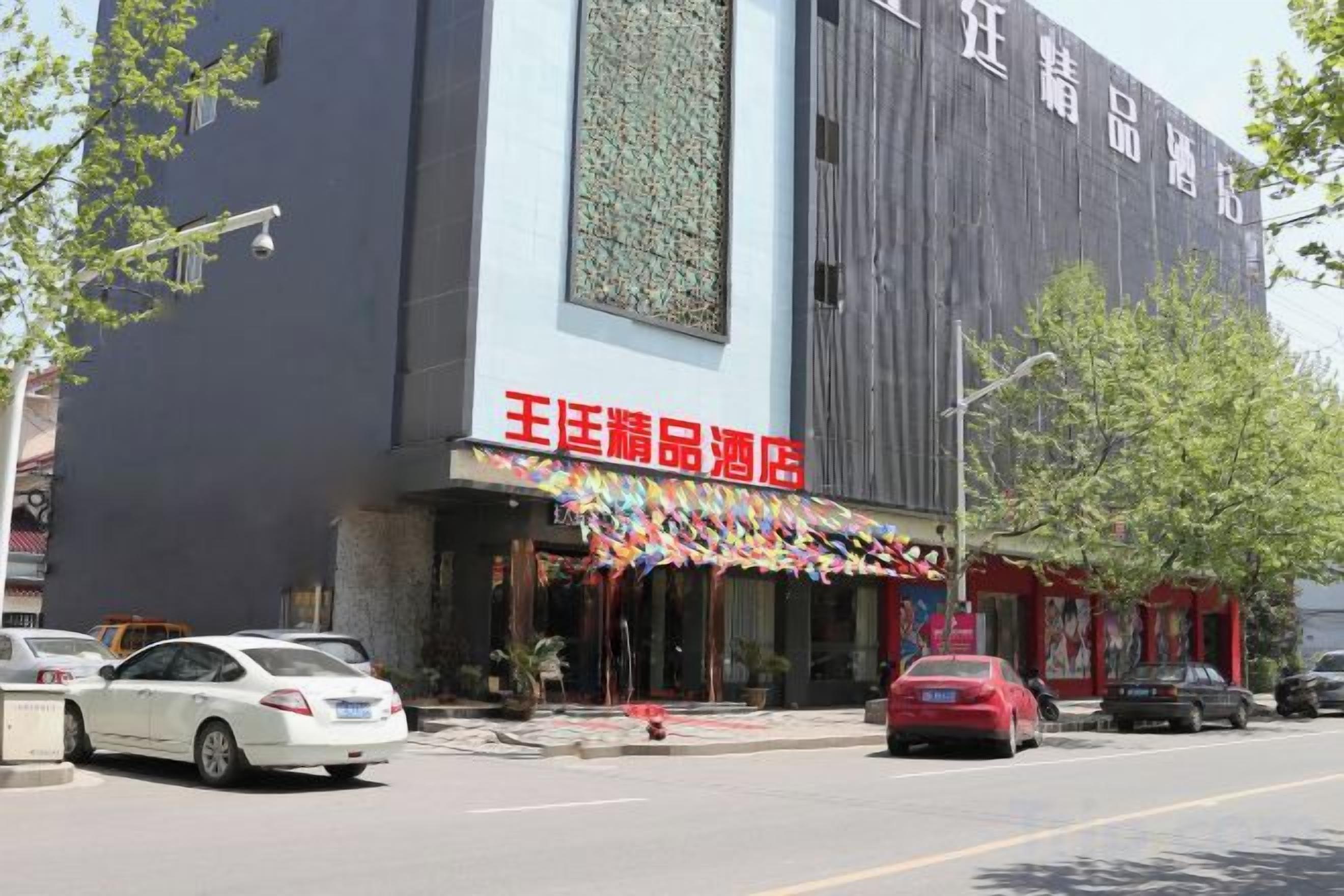 A building with a storefront labeled '王君精品酒店' and several parked cars in front.