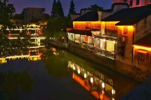 Ein Hotel am Flussufer mit beleuchteten Fenstern und Spiegelbild im Wasser.