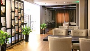 A hotel lobby with a reception desk, seating area, and a decorative wall with glass panels. - Dongfang Haomen Wangting Boutique Hotel (Huzhou)