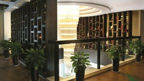 A modern lobby with a glass partition, potted plants, and a decorative chandelier. - Dongfang Haomen Wangting Boutique Hotel (Huzhou)