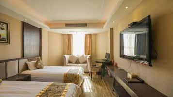 A hotel room with two beds, a desk, a chair, a TV, and a large window.