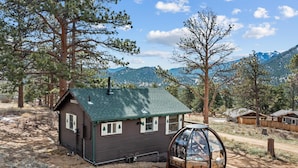 Une cabane avec un toit végétalisé, une petite véranda et une structure vitrée.