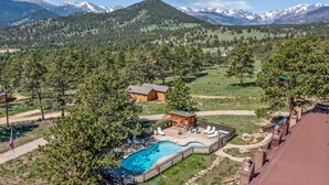 Un complexe hôtelier doté d’une piscine, de chaises longues et offrant une vue sur des montagnes enneigées.