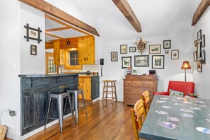 Une cuisine avec des meubles de rangement en bois, un coin bar et une table à manger avec des chaises.