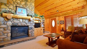 Ein gemütliches Wohnzimmer mit Kamin aus Stein, Holzregalen und einer bequemen Couch.