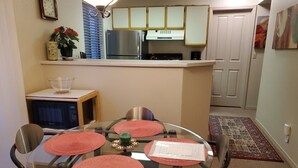 Cocina compacta con refrigerador, microondas y una pequeña mesa de comedor con cuatro sillas.