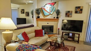 Una sala de estar con sofá, televisión, chimenea y elementos decorativos.