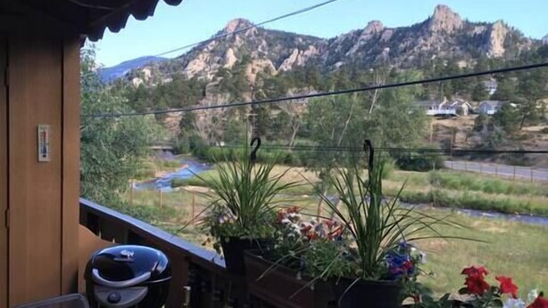 A balcony with a table set for two, overlooking a mountainous landscape.