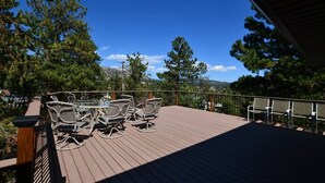 Um deck de madeira com móveis para área externa, com vista para uma paisagem montanhosa.
