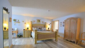 A bedroom with a wooden bed, bedside tables, a wardrobe, and a mirror. - Twin Sisters - 2 bedroom 2 bathroom townhouse (Estes Park)