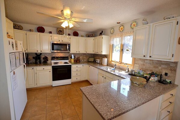 Equipped with a microwave, stove, and oven, this kitchen features a sink and ample storage.