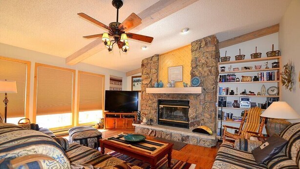 A cozy living room with a fireplace, a television, and a bookshelf. - Twin Sisters - 2 bedroom 2 bathroom townhouse (Estes Park)