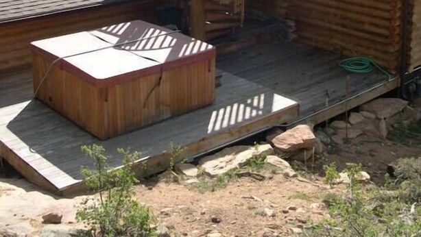Une cabane en bois avec un escalier en colimaçon menant à une terrasse, le tout entouré de montagnes.