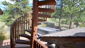 Un escalier en colimaçon en bois menant à une terrasse d’où l’on peut admirer une vue sur les pins.