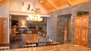 A spacious kitchen with a large island, stone walls, wooden cabinets, and a chandelier.