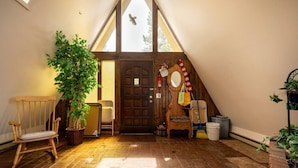 A cozy attic room with a sloped ceiling, a wooden door, a bench, a potted plant, and a small table with a chair. - Peak View - 4 bedroom A-frame with great views (Estes Park)
