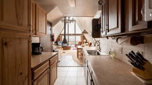 A kitchen with wooden cabinets, a coffee maker, a sink, and a knife block. - Peak View - 4 bedroom A-frame with great views (Estes Park)