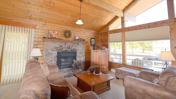 Un salon chaleureux avec une cheminée en pierre, un plafond en bois et de grandes fenêtres.