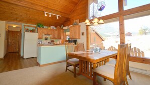 L’intérieur d’une cabane en bois comprend un coin repas, une cuisine et de grandes fenêtres.
