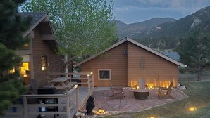 Une cabane en bois dotée d’une terrasse, d’un espace salon extérieur et d’un foyer.