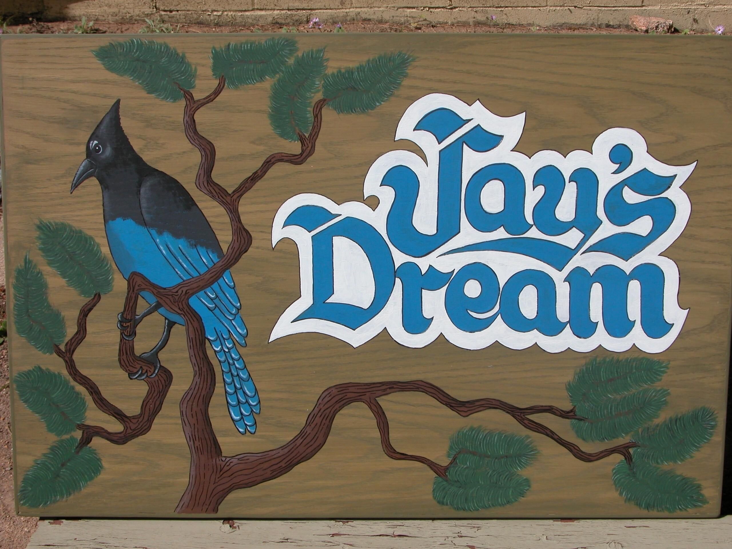 A wooden board with a painted bird and the text "Tav's Dream".