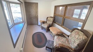 A room with a large window, two wicker sofas, a small bench, and a door. - Lodgepole - 2 bedroom monthly rental - Free WiFi (Estes Park)