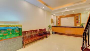 Eine Hotelhalle mit einer Rezeption, einer Bank und einem Aquarium.