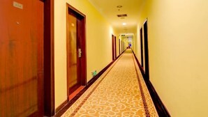 Passadís d'hotel amb portes de fusta, un sòl amb dibuixos i una paret groga.