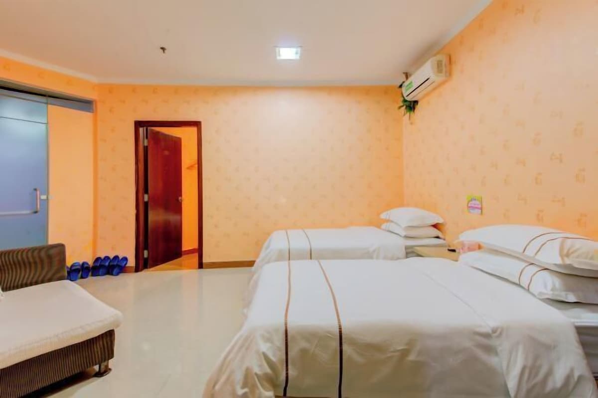 A hotel room with two beds, a sofa, and a small table.