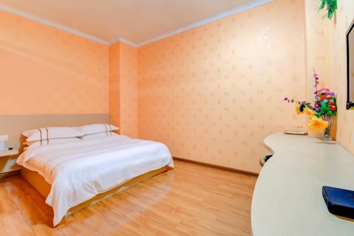 A hotel room with a bed, a nightstand, a desk, and a mirror.