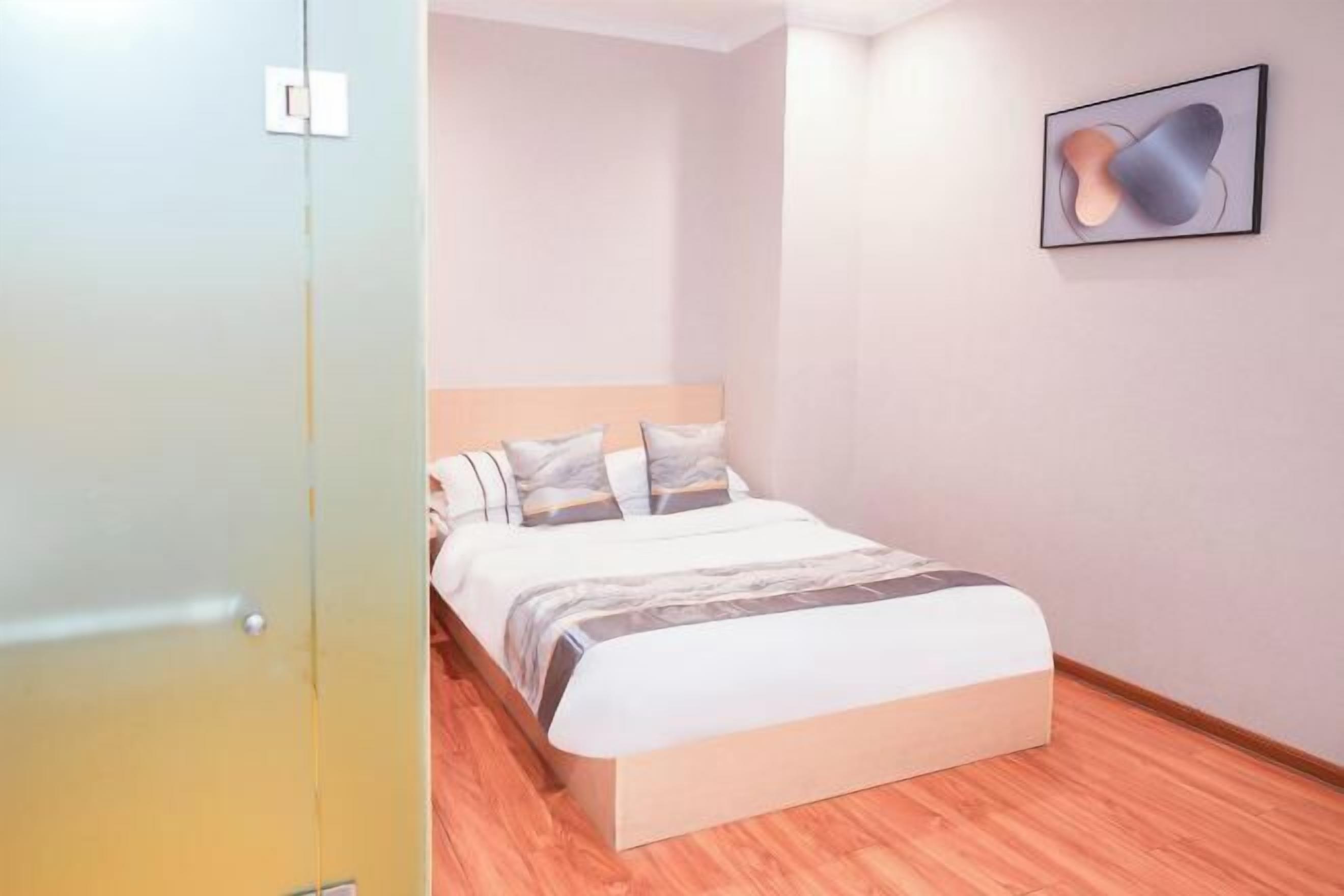 Un dormitorio con una cama, una obra de arte colgada en la pared y suelo de madera.