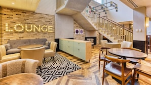 A lounge area with a staircase, seating, and a 'Lounge' sign. - Hub By Premier Inn London Camden (London)