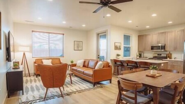A spacious living room with a sofa, chairs, and a dining table. There is a kitchen area with cabinets and a microwave.
