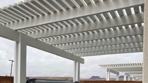 A hot tub under a white pergola with a brick wall and mountains in the background.