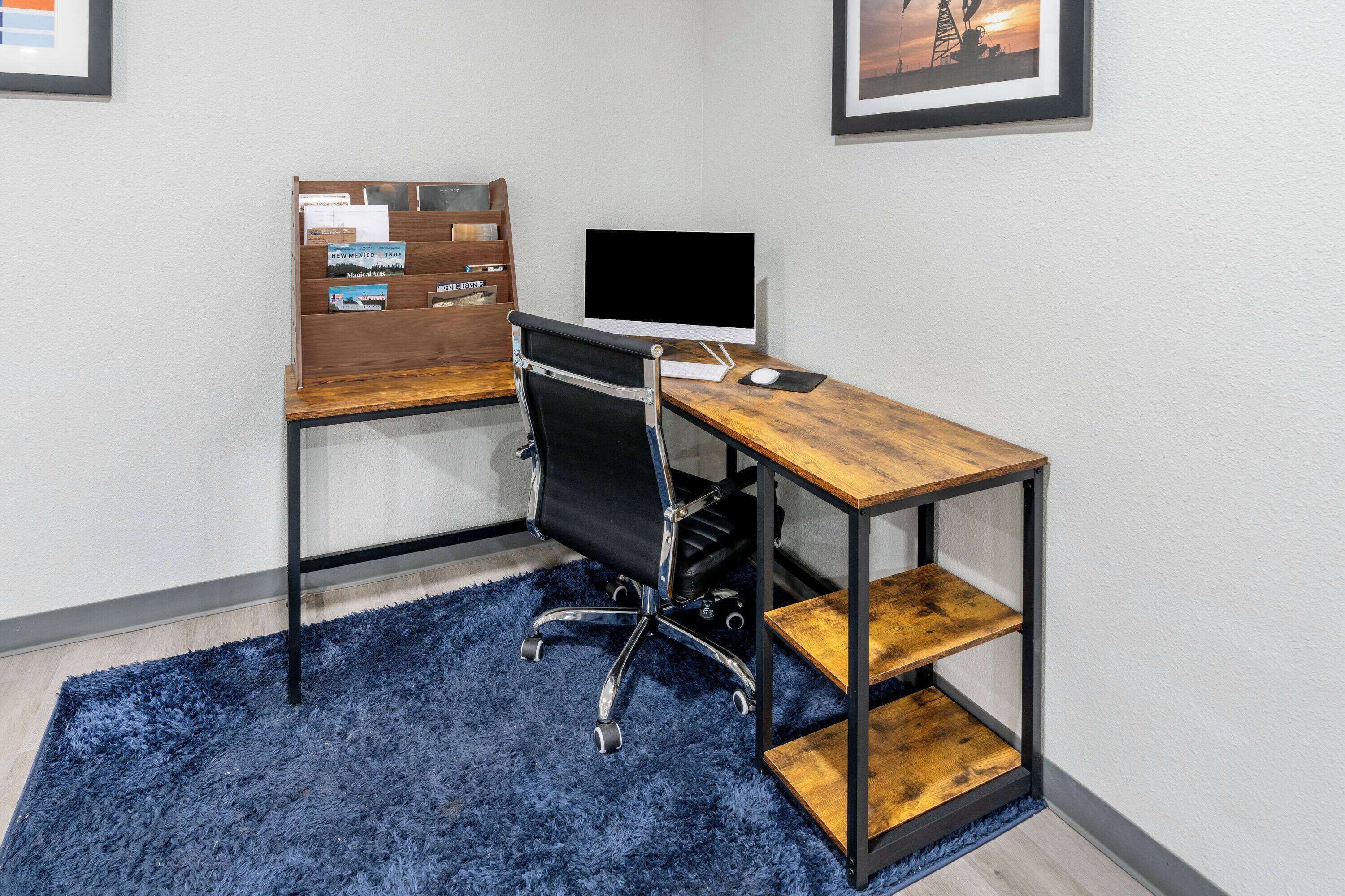 A modern office desk with a computer, a chair, and a bookshelf.
