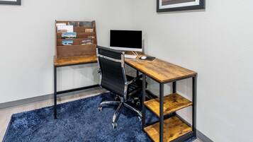 Ein moderner Schreibtisch mit Computer, Stuhl und Bücherregal.