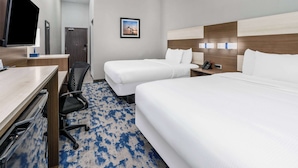 Een hotelkamer met twee bedden, een bureau met stoel, een televisie en een lijst aan de muur.