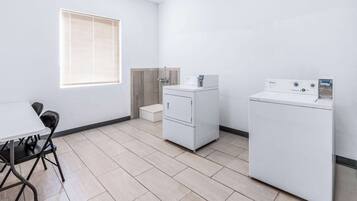 A laundry room with a table, chairs, a washing machine, and a dryer.