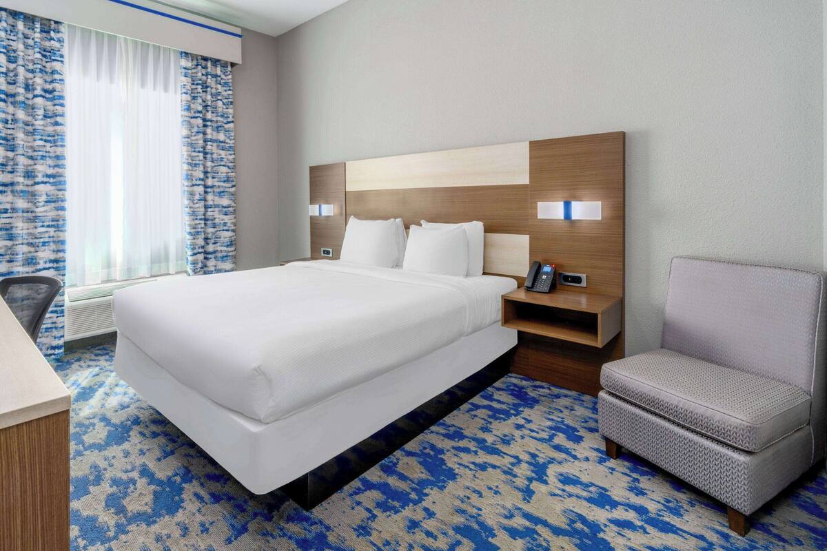 Une chambre d’hôtel avec un grand lit, un bureau, une chaise et une table de chevet avec un téléphone.