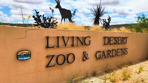 Een bord voor 'Living Desert Zoo & Gardens' met een silhouet van een hert en cactussen op de achtergrond.